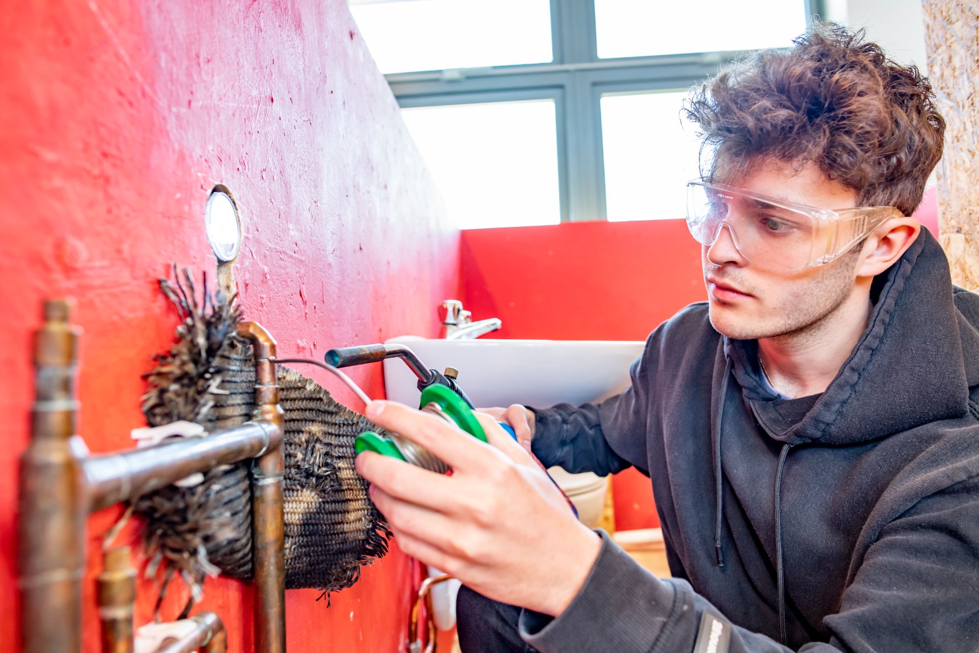 Student wearing goggles and working with a blowtorch