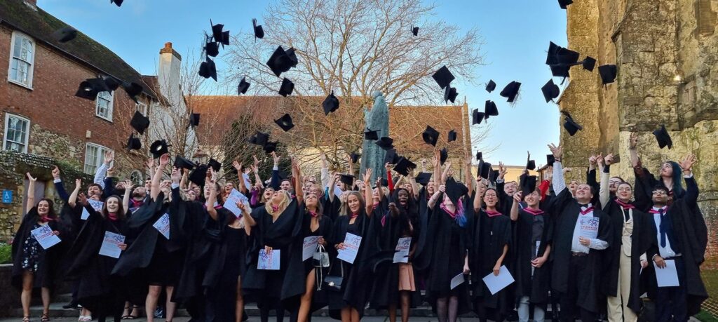 A large group of graduates throwing their graduation caps into the air in celebration.